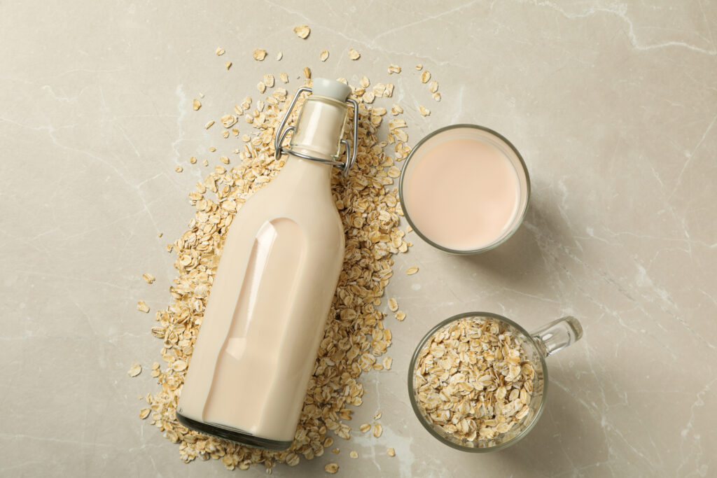 Bottle And Glass With Milk, Oatmeal On Beige Background, Top Vie