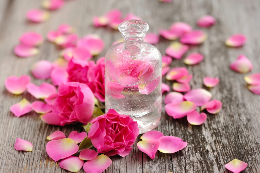 Essential Oil With Rose Petals On Wooden Background